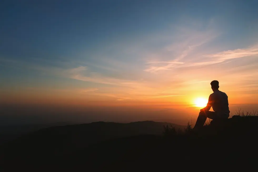 Pessoa contemplando o pôr do sol, simbolizando a busca por significado além da riqueza material.